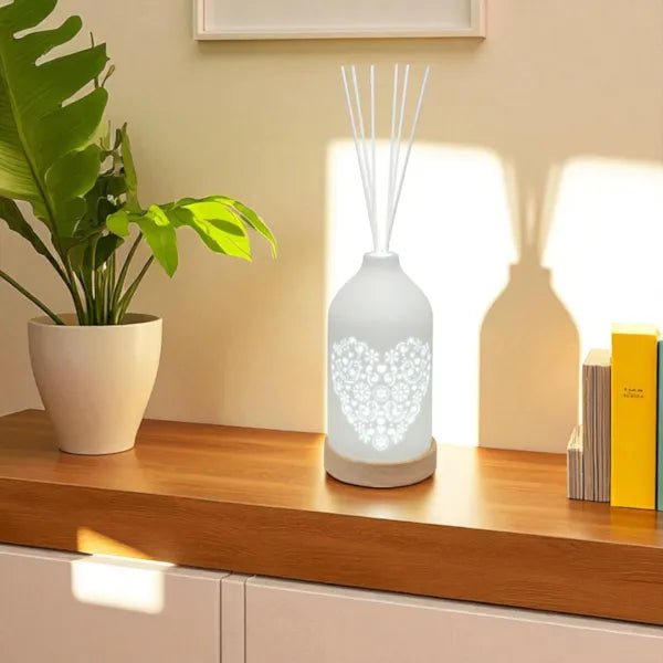 Heart LED reed diffuser glowing on a sideboard next to houseplants and books

