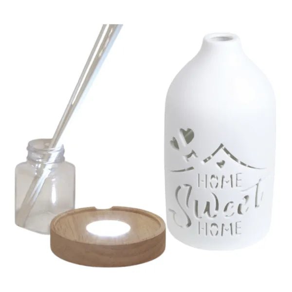 Disassembled LED reed diffuser showing base, glass bottle, reeds, and ceramic cover

