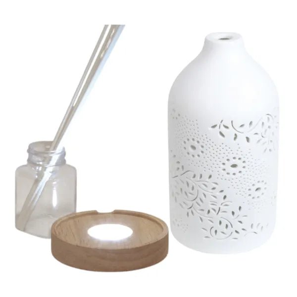 Disassembled reed diffuser with ceramic cover, bottle, LED wood-effect base, and sticks