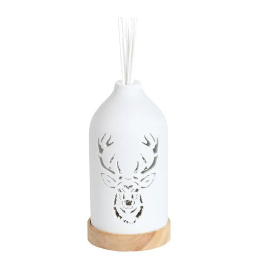White ceramic stag reed diffuser assembled on a wooden base with reed sticks in place.