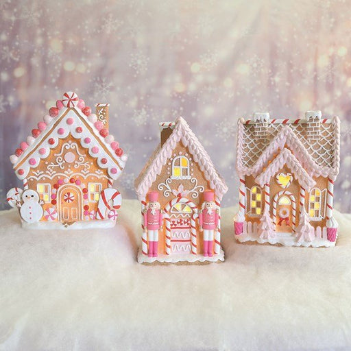 Trio of pink LED gingerbread houses glowing on a snowy tabletop Christmas display.