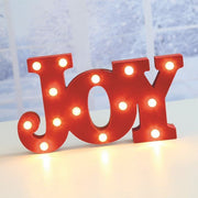 Glowing red JOY LED marquee sign styled on a festive tabletop.