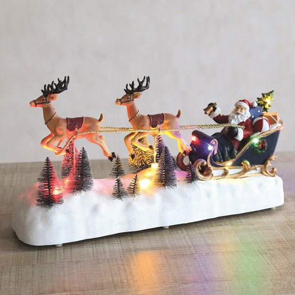 LED Santa sleigh glowing on a tabletop with snowy trees

