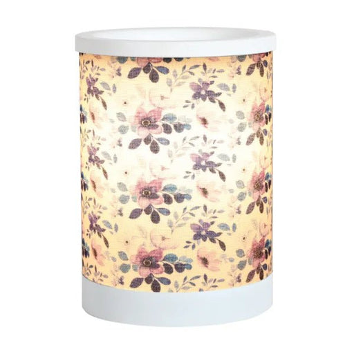 Lilac floral electric wax melt burner switched on, glowing warmly through the floral design.