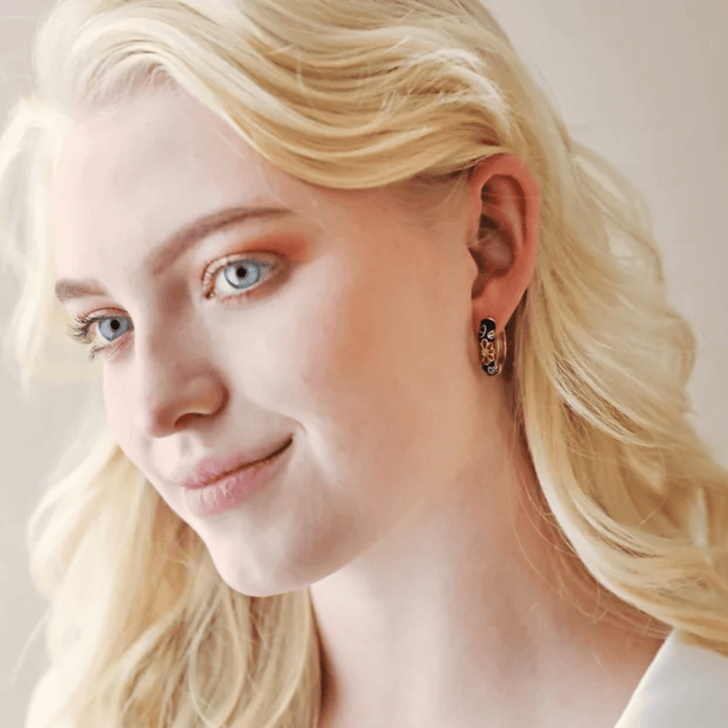 Model wearing black and gold floral enamel hoop earrings