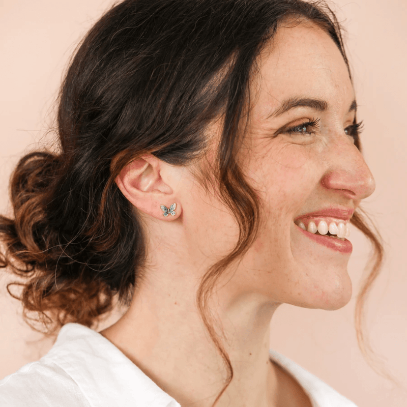 Model wearing Lisa Angel blue and green butterfly stud earrings in gold