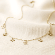 Macro shot of gold plated stainless steel butterfly charm necklace showing textured butterfly charms and fine trace chain.
