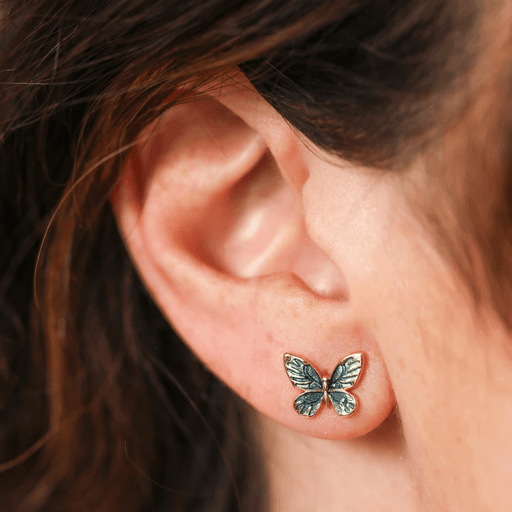 Close-up of a Lisa Angel blue and green butterfly stud earring worn in the ear