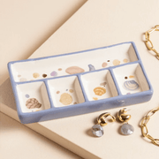 Blue and white ceramic trinket tray with shell illustrations and five compartments, styled with gold jewellery and earrings.