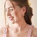 Model wearing Lisa Angel Enamel Lemon gold huggie hoop earrings with layered gold necklaces