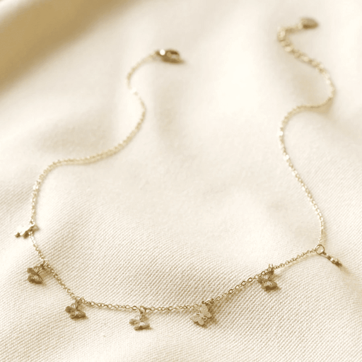 Full view of gold plated stainless steel butterfly charm necklace with seven butterfly charms, lobster clasp and extender chain.