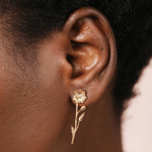 Close-up of a Lisa Angel gold flower and stem drop earring being worn