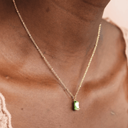 Close-up of a Lisa Angel green enamel frog pendant necklace in gold being worn