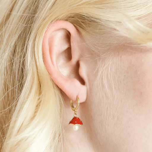 Close-up of Lisa Angel pearl and enamel toadstool huggie hoop earring worn in the ear