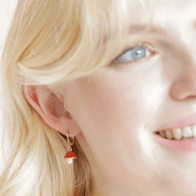 Model wearing Lisa Angel pearl and enamel toadstool huggie hoop earrings in gold