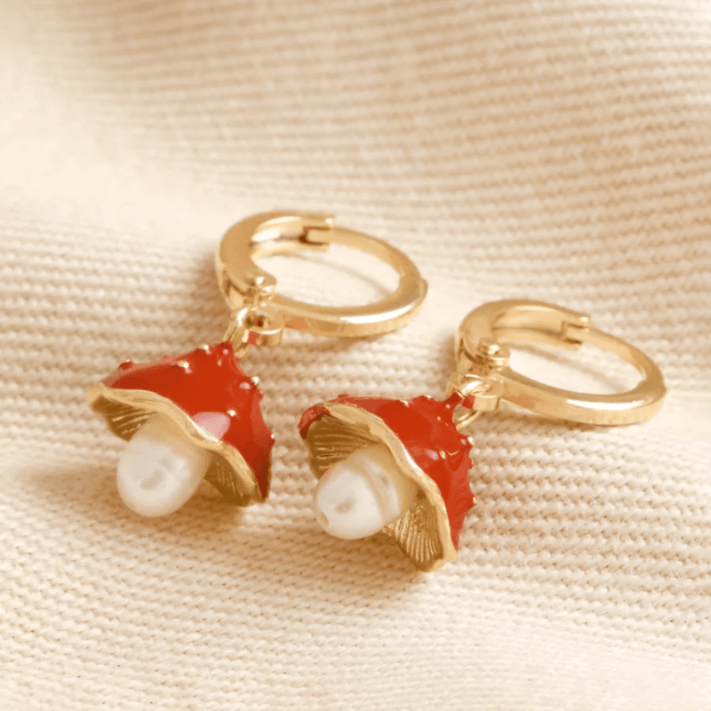 Pair of Lisa Angel gold huggie hoop earrings with red enamel toadstool charms and freshwater pearls