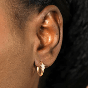 Close-up of a gold stainless steel huggie earring with a cubic zirconia star