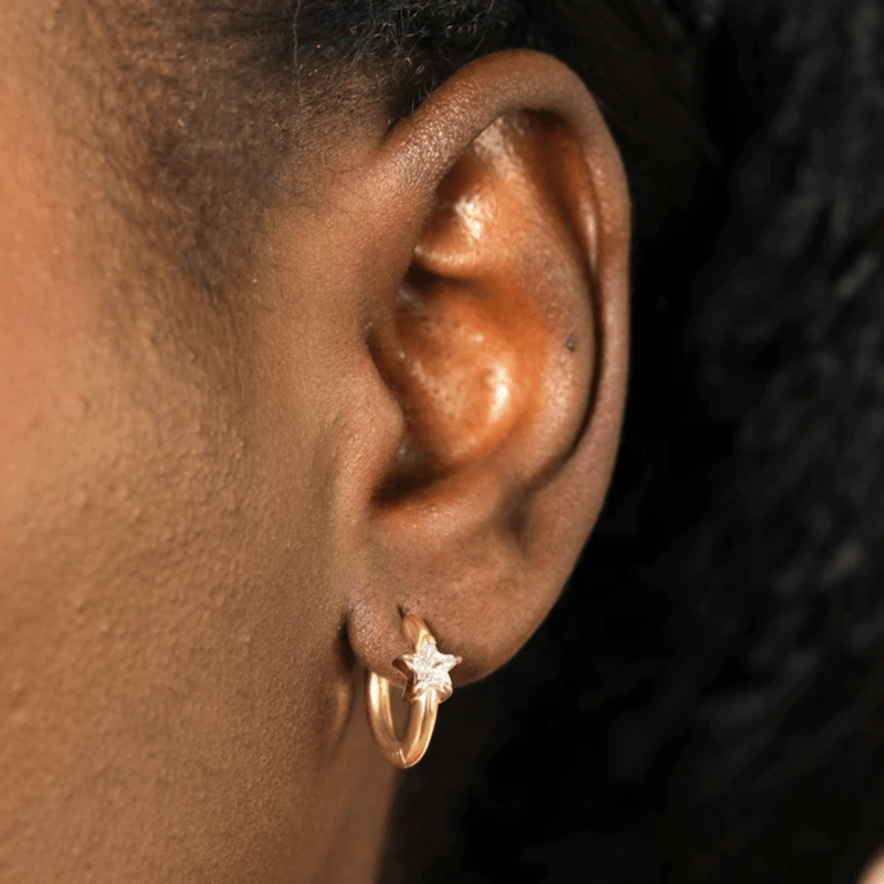 Close-up of a gold stainless steel huggie earring with a cubic zirconia star