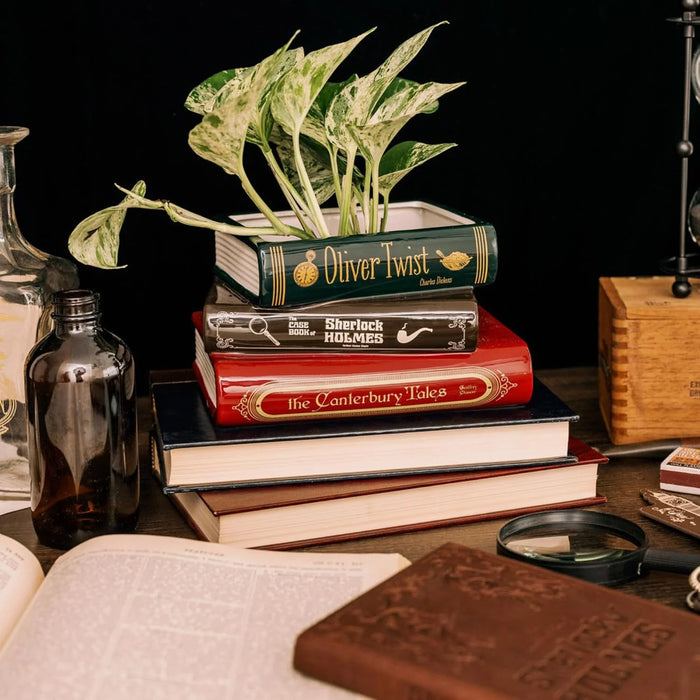 Literary book stack ceramic planter on a desk scene with open books and magnifying glass