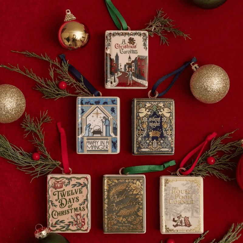 Six decorative book-shaped ornaments displayed together on red fabric, including the Twelve Days of Christmas design