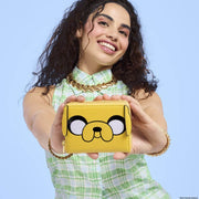Model holding Loungefly Adventure Time Jake wallet; bright yellow Jake face pops – Loungefly wallet lifestyle

