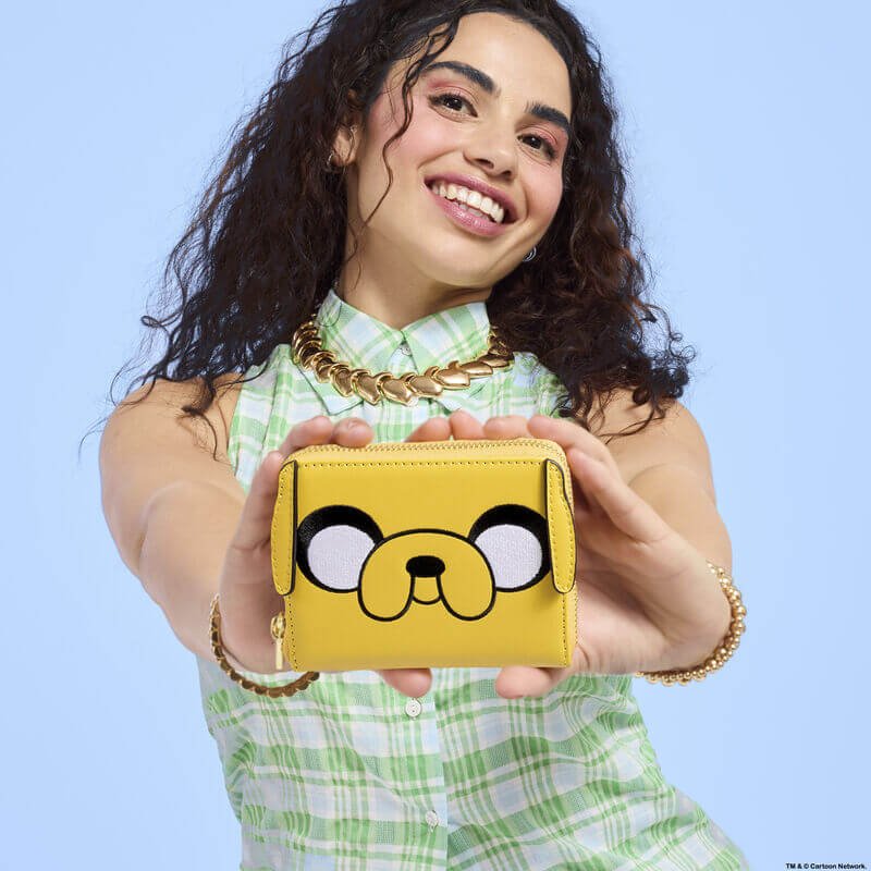 Model holding Loungefly Adventure Time Jake wallet; bright yellow Jake face pops – Loungefly wallet lifestyle

