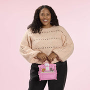 Model holding the Loungefly Disney The Aristocats figural piano crossbody bag by the top handle, shaped like a pink piano.