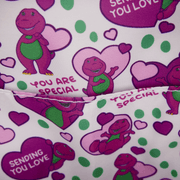 Close-up of the interior lining of the Loungefly Barney mini backpack with Barney character print, hearts and green polka dots.