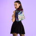 Model wearing the Loungefly Beetlejuice house mini backpack over the shoulder on a purple backdrop
