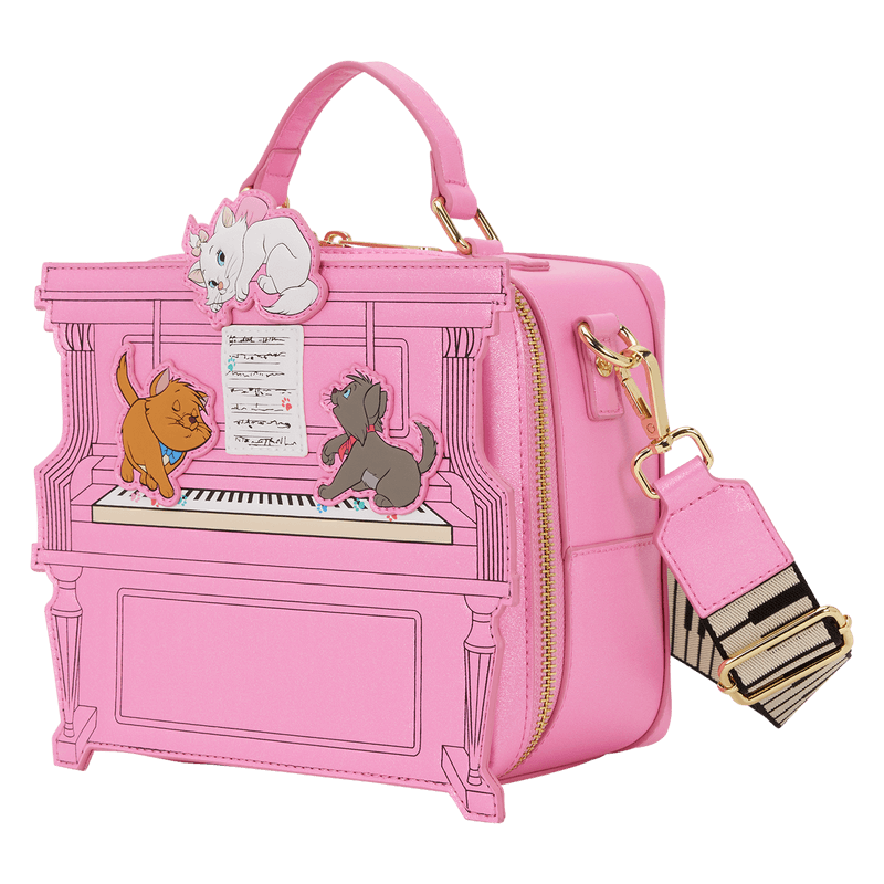 Angled view of the Loungefly Disney The Aristocats figural piano crossbody bag showing the pink piano shape, gold zip and detachable strap.