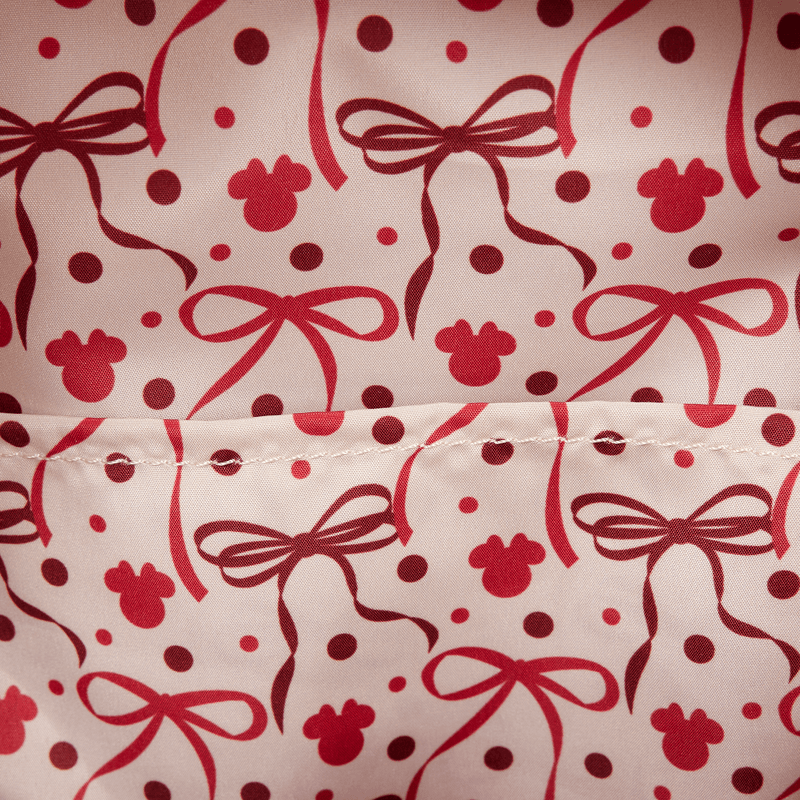 Close-up of the interior lining of the Loungefly Disney Minnie Mouse mini backpack with red bows, polka dots and Mickey icon silhouettes.