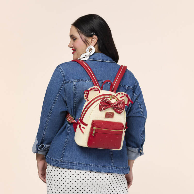 Model wearing the Loungefly Disney Minnie Mouse Rocks The Dots mini backpack, featuring Minnie ears, red accents and a polka dot bow.
