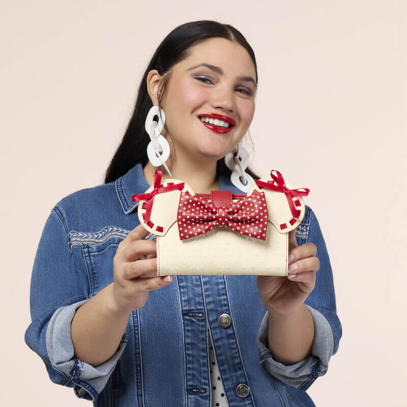 Model holding the Loungefly Disney Minnie Rocks The Dots wallet featuring Minnie ears, a red polka dot bow and cream details.