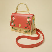 Studio shot of Loungefly Moana crossbody showing red strap, gold chain and floral trim