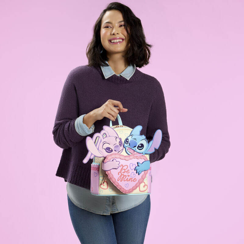 Model holding Loungefly Stitch and Angel Be Mine mini backpack in pastel colours with large heart front pocket