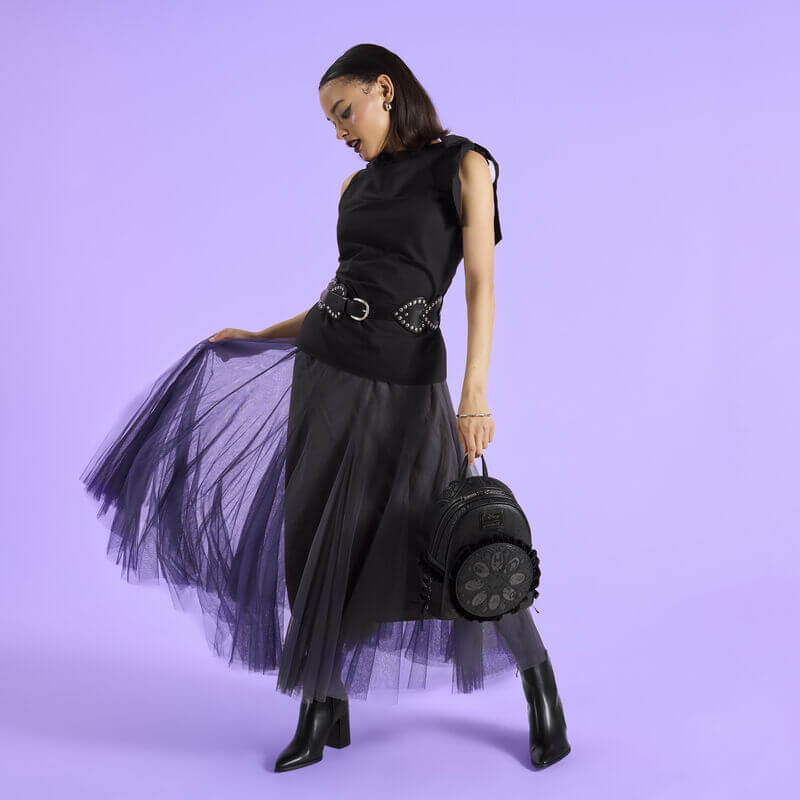 Model holding a black Loungefly Disney Villains mini backpack with ruffled front medallion