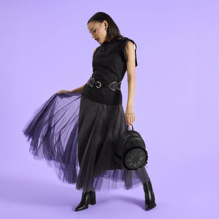 Model holding a black Loungefly Disney Villains mini backpack with ruffled front medallion