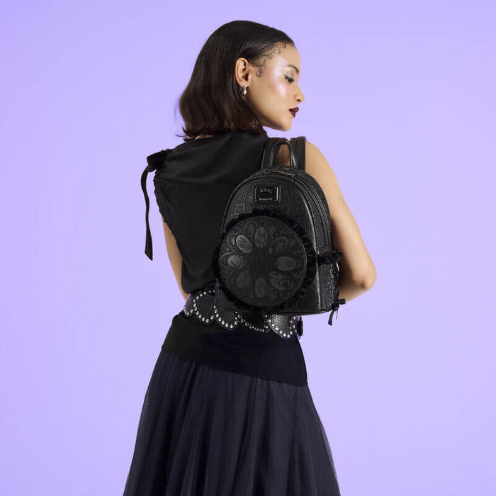 Model wearing the black Loungefly Disney Villains mini backpack showing embossed texture and round front panel