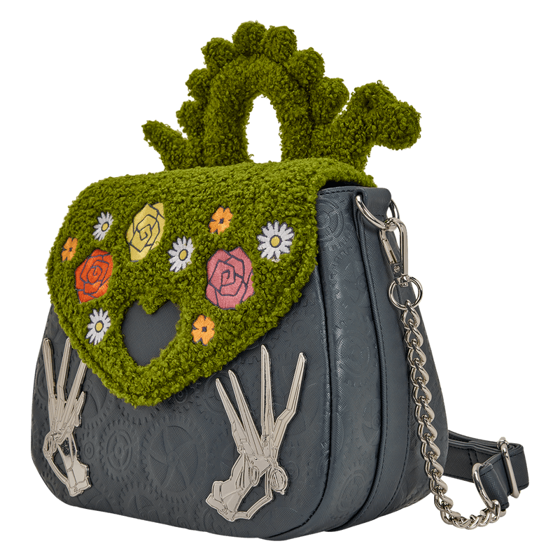 Angled view of the Loungefly Edward Scissorhands crossbody bag showing the chain strap, textured green flap and embossed gear pattern.