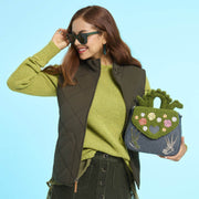 Model holding the Loungefly Edward Scissorhands crossbody bag with green textured flap, embroidered flowers and silver scissorhand details.