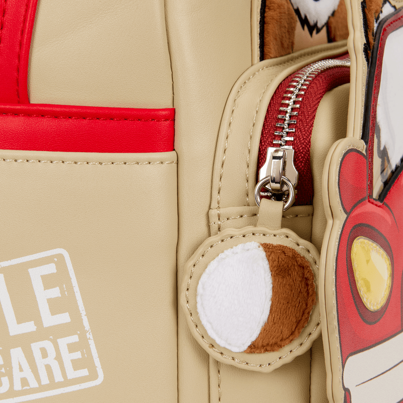 Close-up of zipper pull and applique detail on the Loungefly Gizmo mini backpack with red trim.
