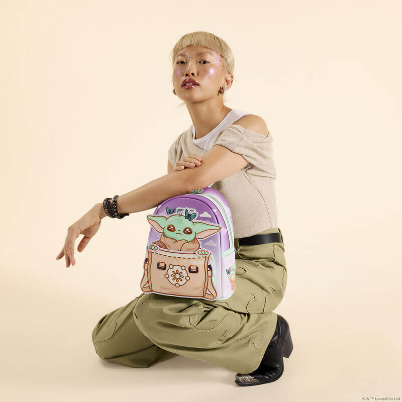 Model holding Loungefly Star Wars Grogu mini backpack with butterfly sky design and satchel applique