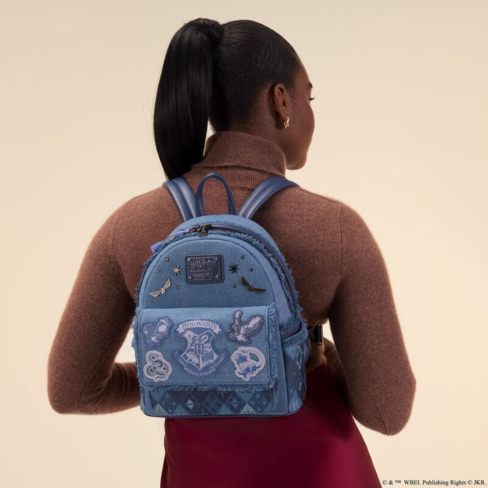 Model wearing the Loungefly Harry Potter denim mini backpack on the back with crest and patches visible.