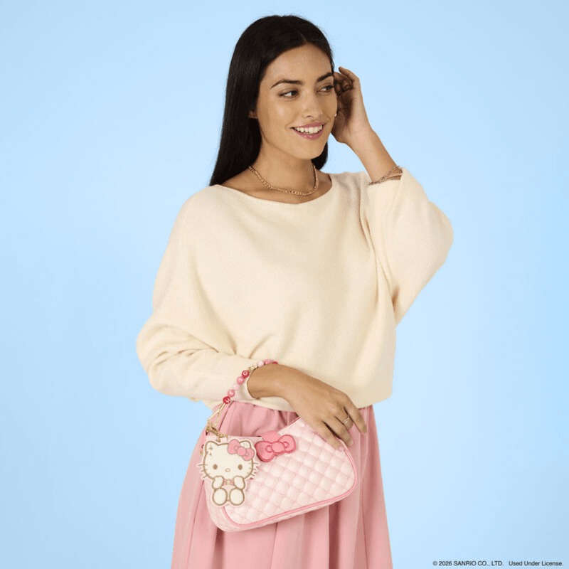 Model carrying the Loungefly Hello Kitty Holiday Quilted Crossbody Bag by its pink and red beaded handle