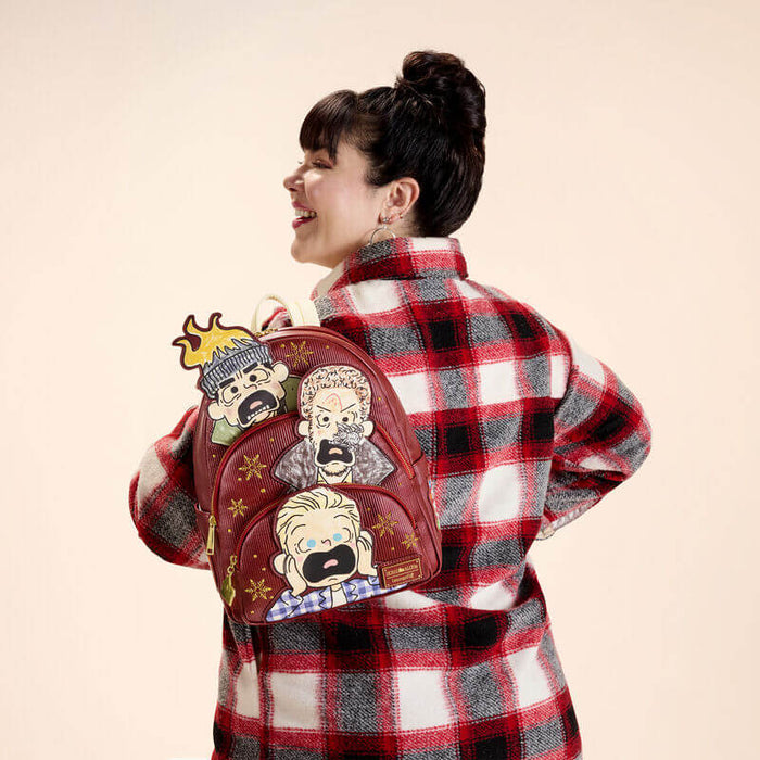 Model wearing Loungefly Home Alone Wet Bandits mini backpack on back, side view.