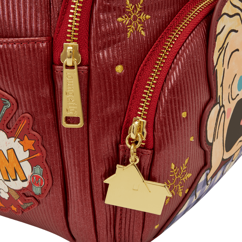 Close-up of gold house zip charm and snowflake detail on red Loungefly Home Alone backpack.