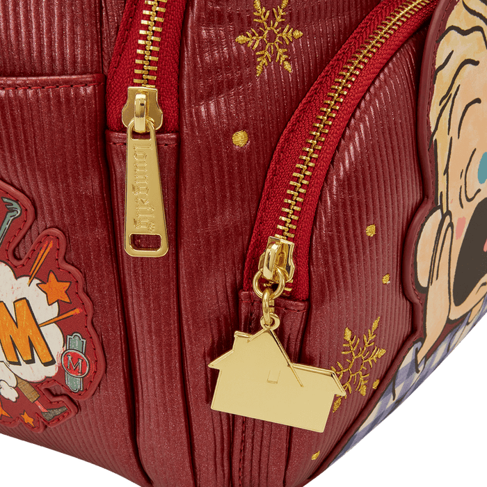 Close-up of gold house zip charm and snowflake detail on red Loungefly Home Alone backpack.