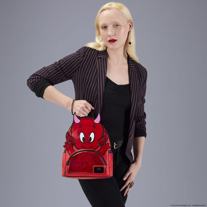 Model holding the Loungefly Hot Stuff mini backpack by the top handle, showing size and front.