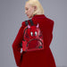 Model wearing the Loungefly Hot Stuff mini backpack on the back, 3D horns and red devil face visible.