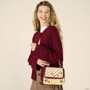 Model wearing Loungefly Disney Lady and the Tramp Spaghetti Crossbody Bag with cream and burgundy pasta-inspired design